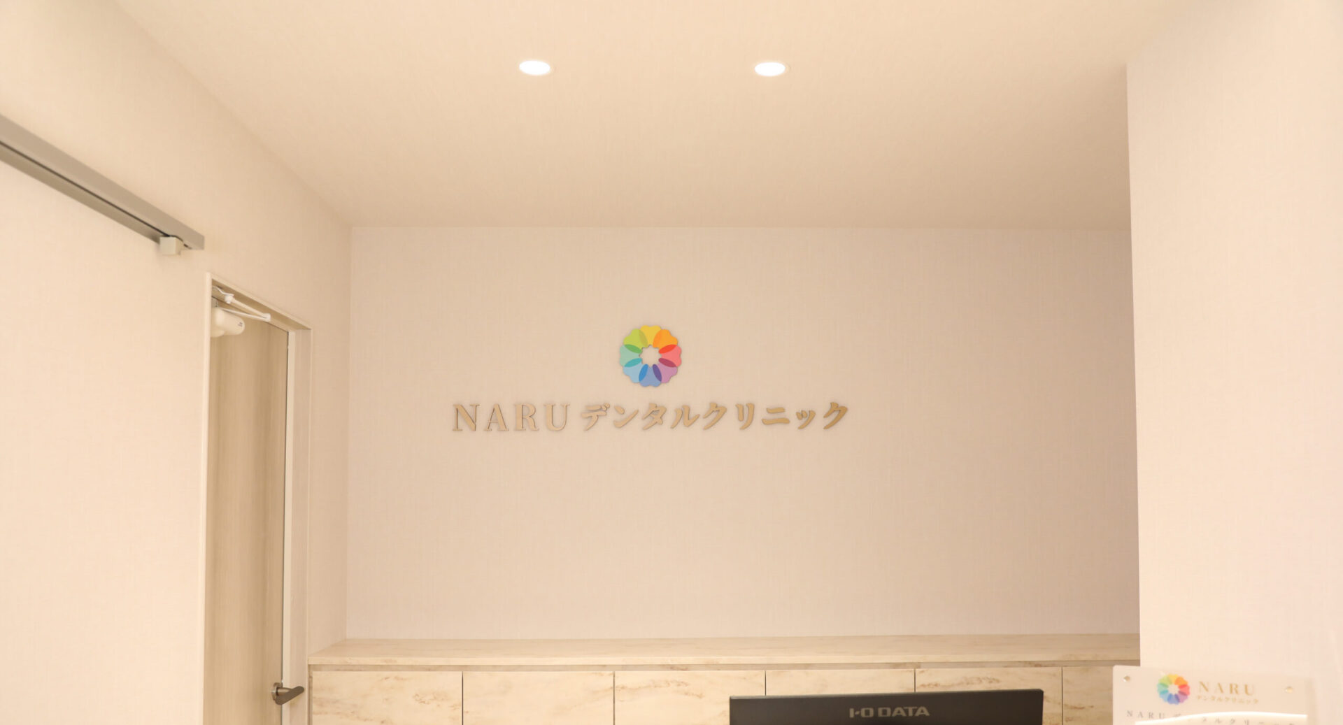 NARUデンタルクリニックの受付カウンターとロゴ